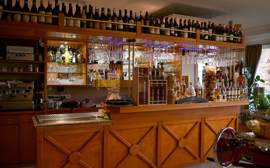 A wooden bar with hanging glasses and bottles behind the bar.