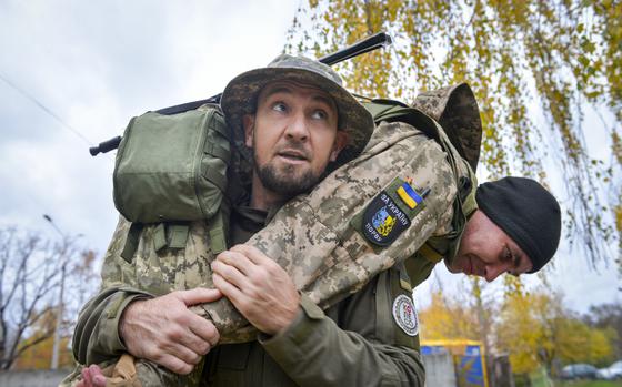 Oleksii Bozhko hefts a Ukrainian soldier as he demonstrates the firefighter's carry, a method of lifting an injured casualty out of a dangerous area, during training outside Kyiv, Ukraine on Oct. 27, 2022. Before the Russian invasion of Ukraine in 2022, Bozhko enjoyed spending his days kitesurfing on lakes and rivers.