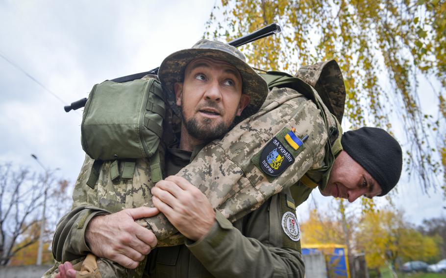 Oleksii Bozhko hefts a Ukrainian soldier as he demonstrates the firefighter’s carry, a method of lifting an injured casualty out of a dangerous area, during training outside Kyiv, Ukraine, on Oct. 27, 2022. Before the Russian invasion, Bozhko enjoyed spending his days kitesurfing on lakes and rivers.