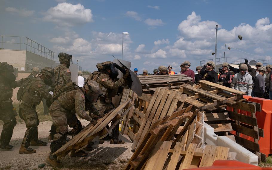 U.S. soldiers remove barricades during the Operation Bronze Shield training exercise June 14, 2023, at the Joint Multinational Training Center in Hohenfels, Germany. Rioters played by soldiers from the 1st Battalion, 4th Infantry Regiment throw fake rocks at the incoming forces.