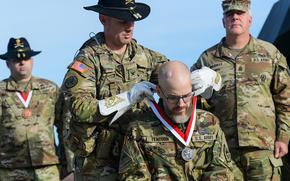 Jay Tenison, an Army tanker veteran diagnosed with terminal cancer, is awarded the Order of St. George by Army Col. Ryan Kranc, the commander of the 316th Cavalry Brigade, at Fort Moore, Ga., on Dec. 5, 2023. The award recognizes achievement among tankers and cavalry troopers. Tenison received the honor after firing a tank one last time. (Corey Dickstein/Stars and Stripes)