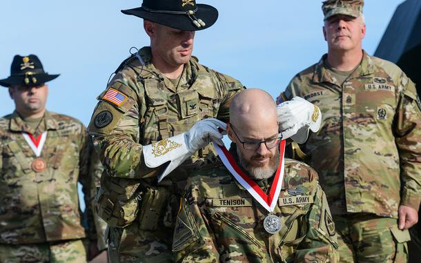 Jay Tenison, an Army tanker veteran diagnosed with terminal cancer, is awarded the Order of St. George by Army Col. Ryan Kranc, the commander of the 316th Cavalry Brigade, at Fort Moore, Ga., on Dec. 5, 2023. The award recognizes achievement among tankers and cavalry troopers. Tenison received the honor after firing a tank one last time. (Corey Dickstein/Stars and Stripes)