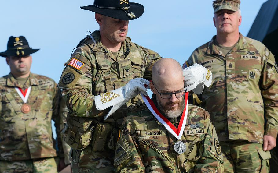 Jay Tenison, an Army tanker veteran diagnosed with terminal cancer, is awarded the Order of St. George by Army Col. Ryan Kranc, the commander of the 316th Cavalry Brigade, at Fort Moore, Ga., on Dec. 5, 2023. The award recognizes achievement among tankers and cavalry troopers. Tenison received the honor after firing a tank one last time. 