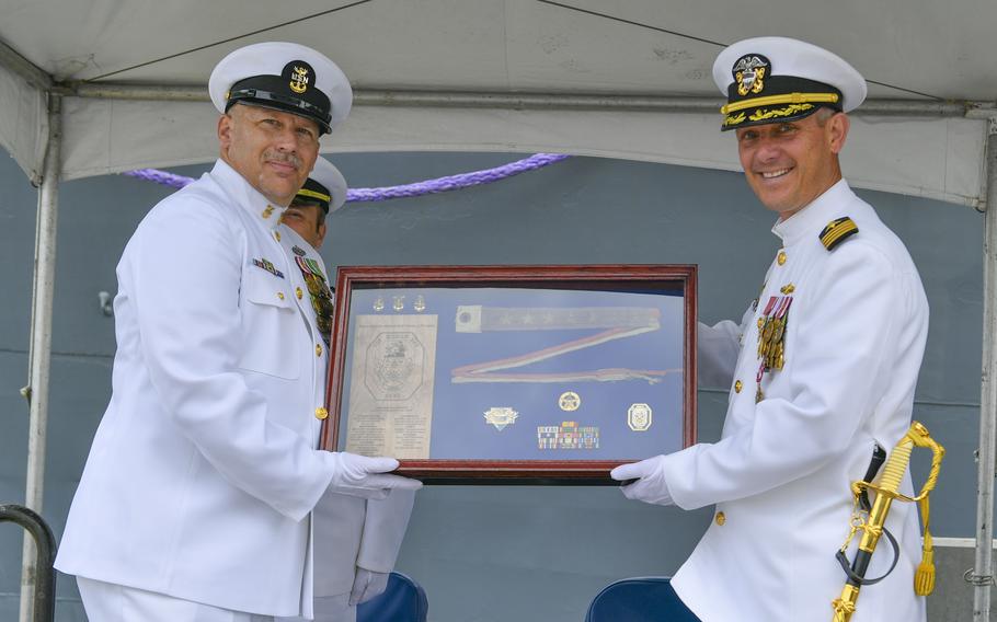 Capt. Brandon J. Burkett, commanding officer of the Ticonderoga-class guided-missile cruiser USS Mobile Bay (CG 53), right, and Command Master Chief Neal Olds, command master chief of Mobile Bay, display the commissioning pennant during the decommissioning ceremony of Mobile Bay.