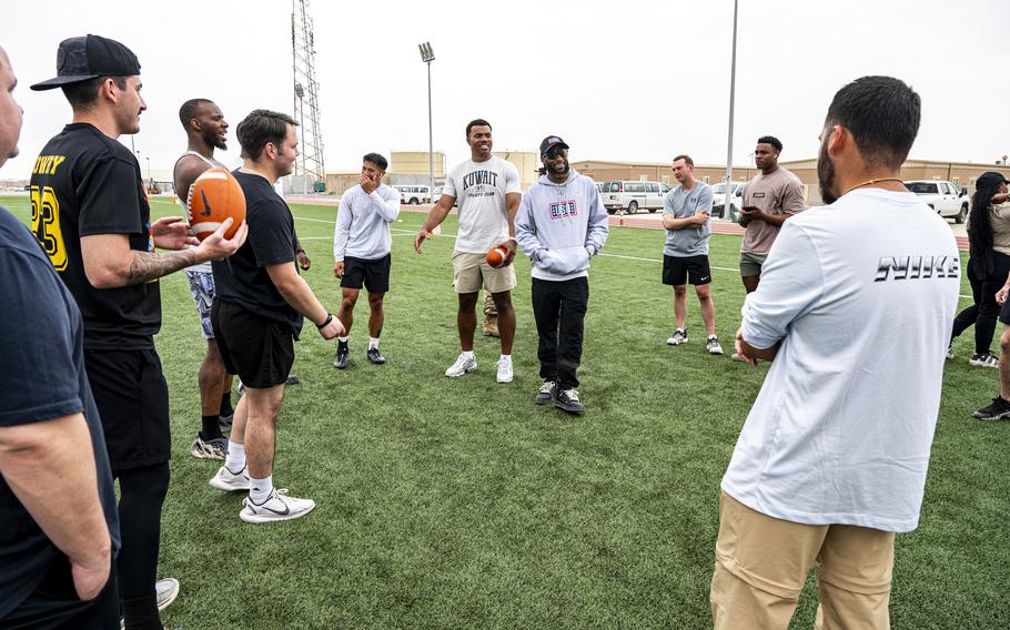 NFL players and airmen participate in a football drill