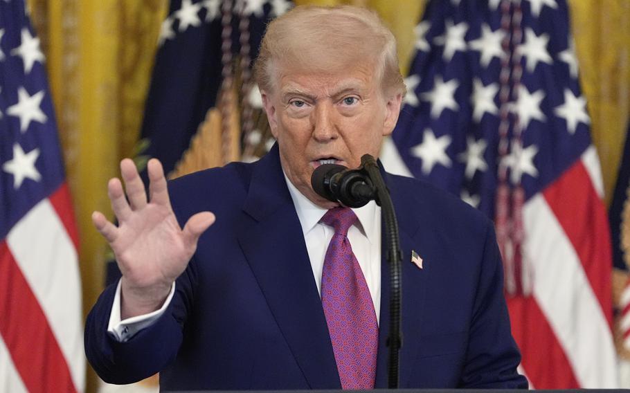 Trump gestures with his right hand while standing at a microphone.