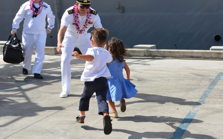 Children race toward their father after he walks onto the pier from the destroyer Daniel Inouye at Joint Base Pearl Harbor-Hickam, Hawaii, Thursday, Nov. 18, 2021.