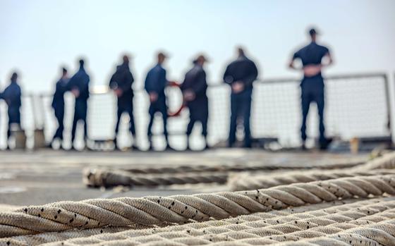 Sailors stand near the rails of a ship in South Korea.