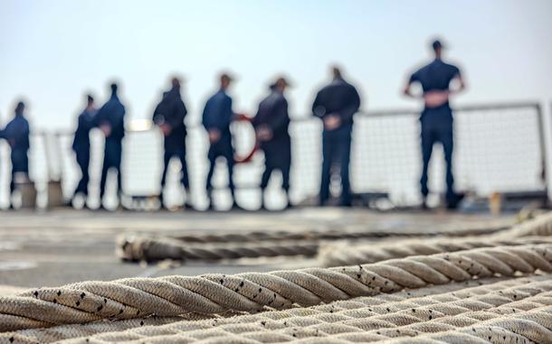 Sailors stand near the rails of a ship in South Korea.