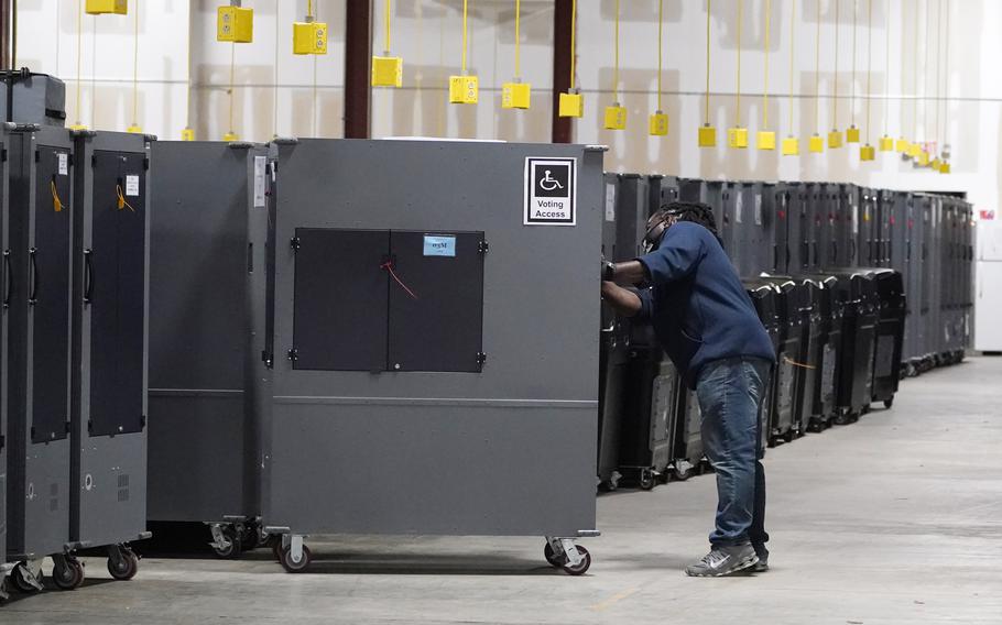 A worker returns voting machines to storage at the Fulton County Election preparation Center on Nov. 4, 2020 in Atlanta, Ga. The list of security breaches at local election offices since the 2020 election keeps growing, with investigations ongoing in at least three states, Colorado, Georgia and Michigan. Security experts say the breaches by themselves have not necessarily increased threats to the November elections, but say they increase the possibility that rogue election workers could access election equipment to launch attacks.