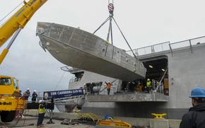 An unmanned surface vehicle is loaded onto the littoral combat ship USS Canberra on April 23, 2024, at Naval Base San Diego, Calif., as part of the first embarkation of the mine countermeasures mission package. The Navy plans to deploy littoral combat ships to the Middle East for mine countermeasure operations.