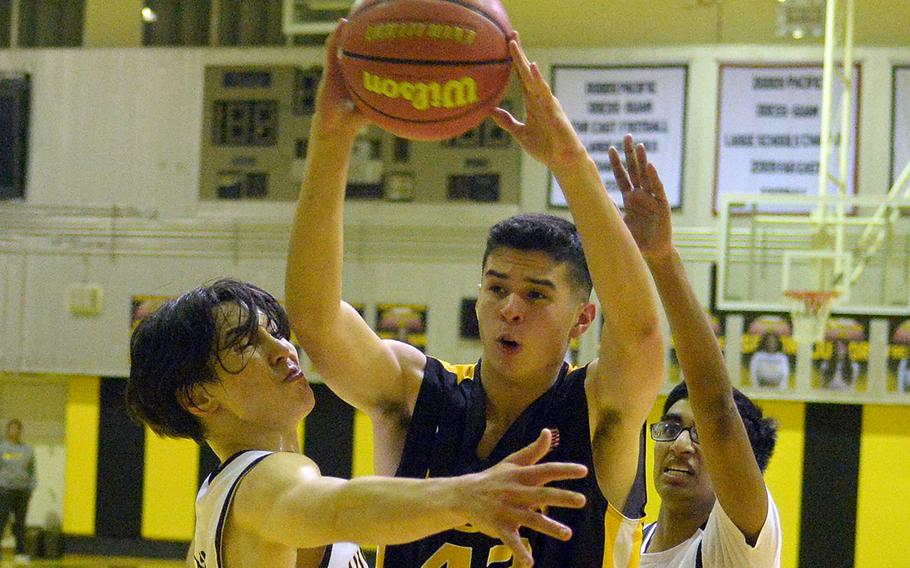 Kadena's Jason Laid tries to pass through American School In Japan's Kian Takizawa and Shaan Shah during Friday's inter-district boys basketball game. The Panthers won 58-35.