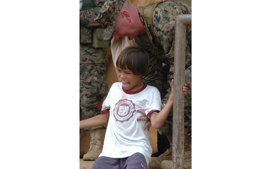 An orphaned girl, whose family was swept away by a mud slide, is comforted by a U.S. Navy chaplain who helped the girl reach an orphanage.