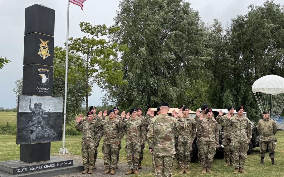Enlisted soldiers stand in formation facing an officer.