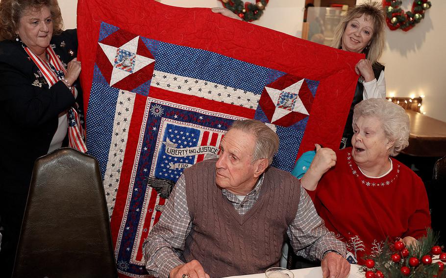 World War II veteran Guy Atkinson, 98, of Massillon is surprised with a handmade quilt from the Quilts of Valor Foundation while having dinner with friends Friday at the Massillon Eagles #190 club. His daughter Betsy Atkinson is seated to his right.