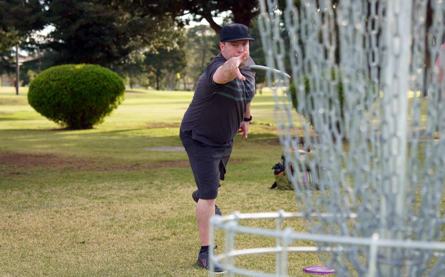 Air Force Senior Master Sgt. Joshua DeMotts takes aim at a disc-golf basket on the Par 3 course at Yokota Air Base, Japan, April 6, 2023.