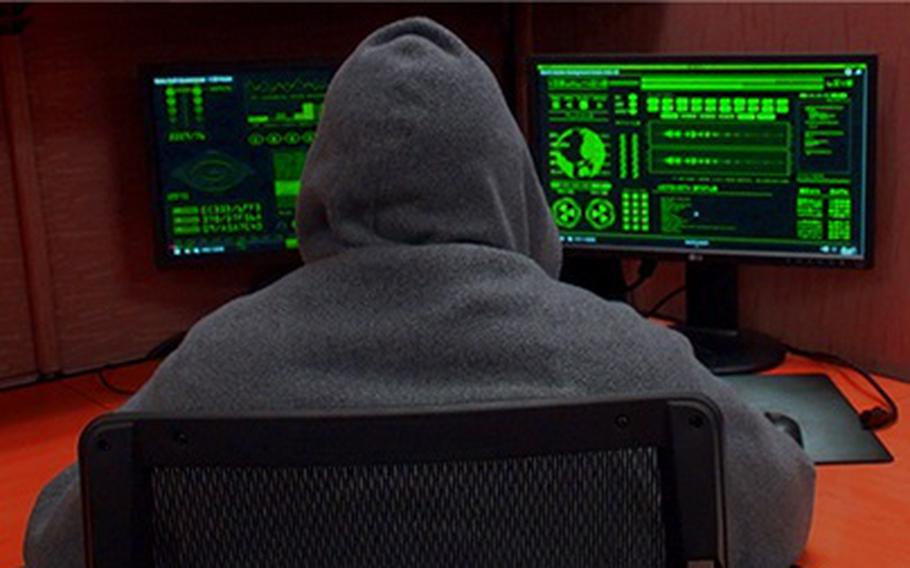 An image of a man in a hoodie looking at two computer monitors with green displays, against a red background.