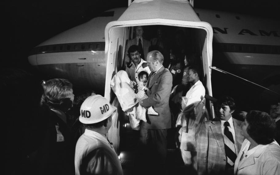 President Gerald Ford carries a Vietnamese baby from “Clipper 1742” after it landed in San Francisco.
