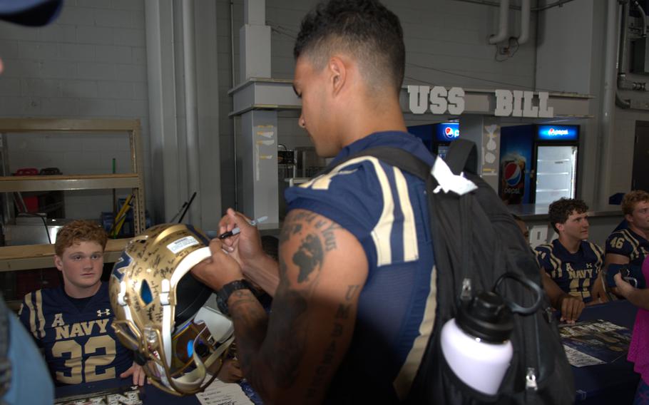 Senior wide receiver Jayden Umbarger signs a helmet at Navy Football FanFest on July 29, 2023, on the concourse of Navy-Marine Corps Memorial Stadium in Annapolis, Md.