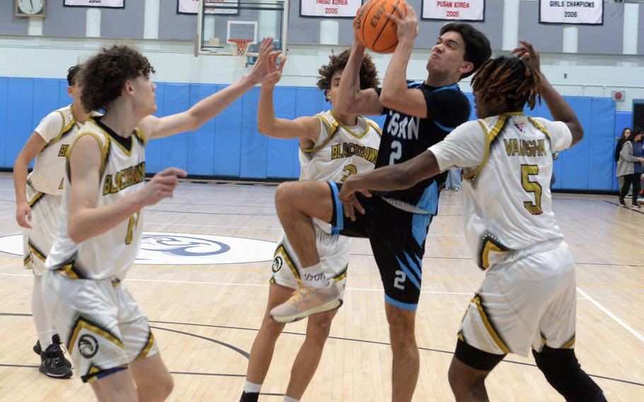 Osan's M.J. Siebert puts up a shot between Humphreys defenders during Friday's DODEA-Korea boys basketball game. The Blackhawks won the inter-division game 59-50.