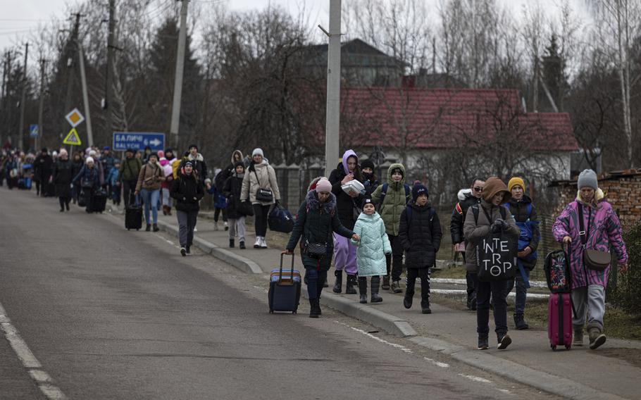 Groups of Ukrainian refugees walk along the road between Lviv and Shehyni, in Volytsya, Ukraine, Saturday March 5, 2022. The number of Ukrainians forced from their country since the Russian invasion has been increasing on a daily basis. 