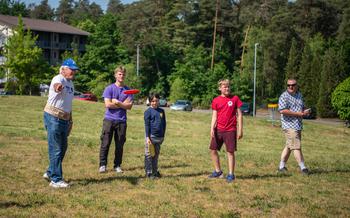 A man throws a flying disc on a disc golf course while others watch.