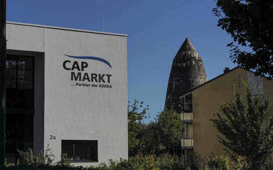 A Spitzbunker on Pariser Strasse is flanked by a supermarket and an apartment building, illustrating how Kaiserslautern's urban growth has integrated these wartime relics into the fabric of the city. The bunker, once a vital air raid shelter, now quietly coexists with the daily life of the community.