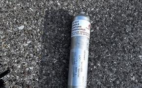A metal canister of phosphorous pyrotechnic is seen on the ground.