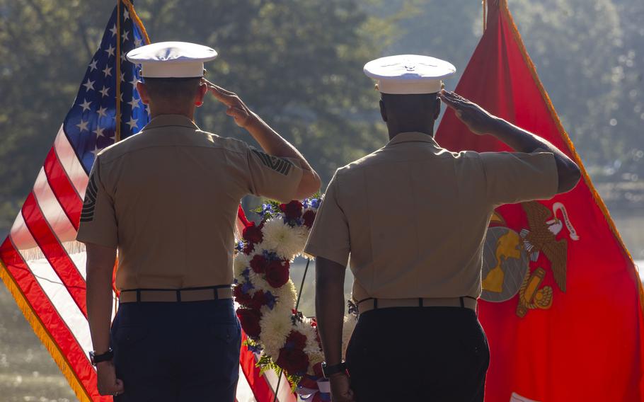Two Marines salute a wreath.