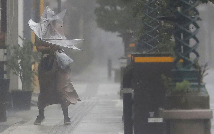 A woman makes her way through the strong wind and rain in Miyazaki, southern Japan, Sunday, Sept. 18, 2022, as a powerful typhoon pounded southern Japan.