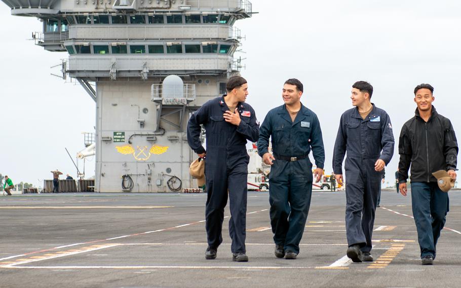 Sailors walk the flight deck of the aircraft carrier USS Theodore Roosevelt in the Pacific Ocean on Oct. 25, 2023.