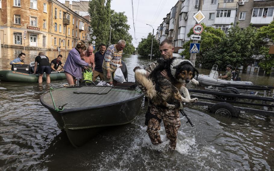 A Ukrainian soldier carries a pet dog through flooded Kherson city on Wednesday as residents evacuate their homes.