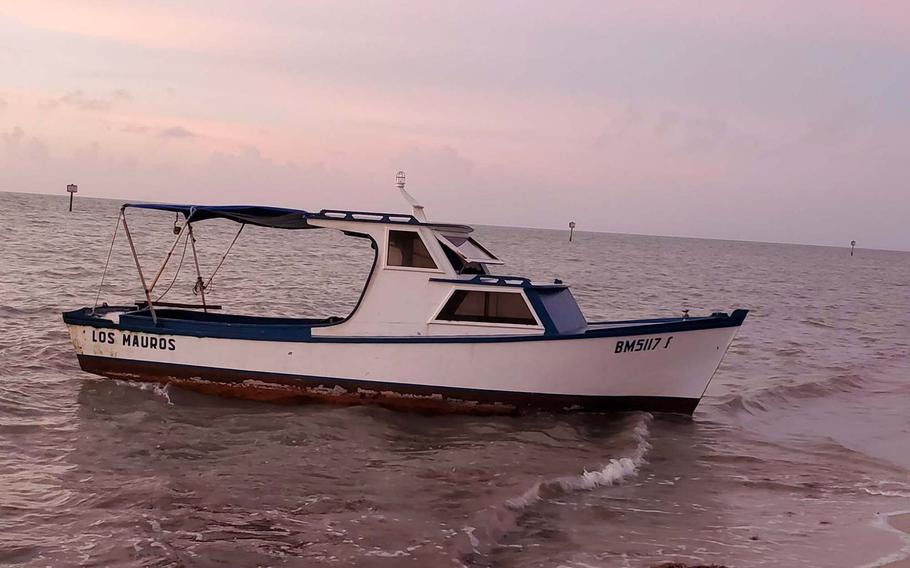 A wooden fishing boat rests in the shallow water on the shore of Key West on Saturday, Dec. 18, 2021. The boat, along with another fishing vessel, carried 37 migrants from Cuba, according to the U.S. Border Patrol. 