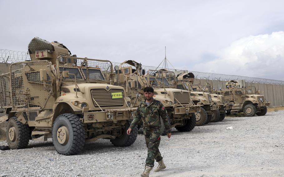 An Afghan army soldier walks past Mine Resistant Ambush Protected vehicles, MRAP, that were left after the American military left Bagram air base, in Parwan province north of Kabul, Afghanistan, Monday, July 5, 2021.