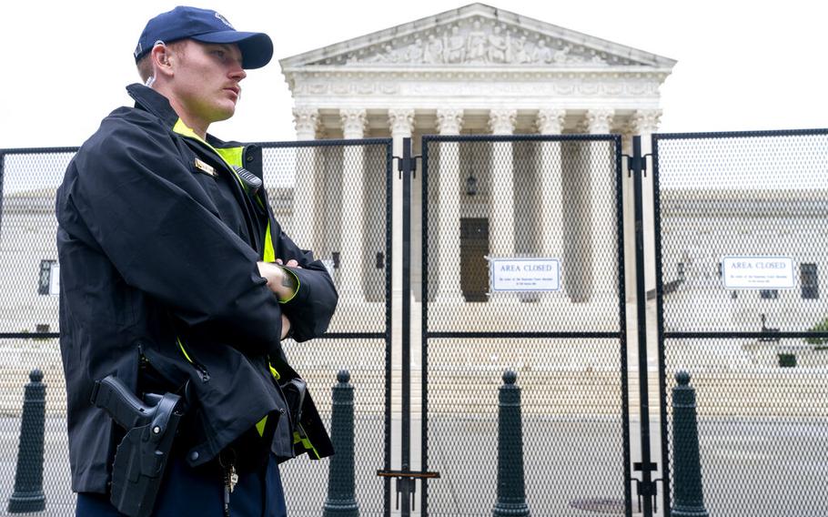 A Capitol Police Officer works by the anti-scaling fencing outside the Supreme Court, Thursday, June 23, 2022, in Washington. 