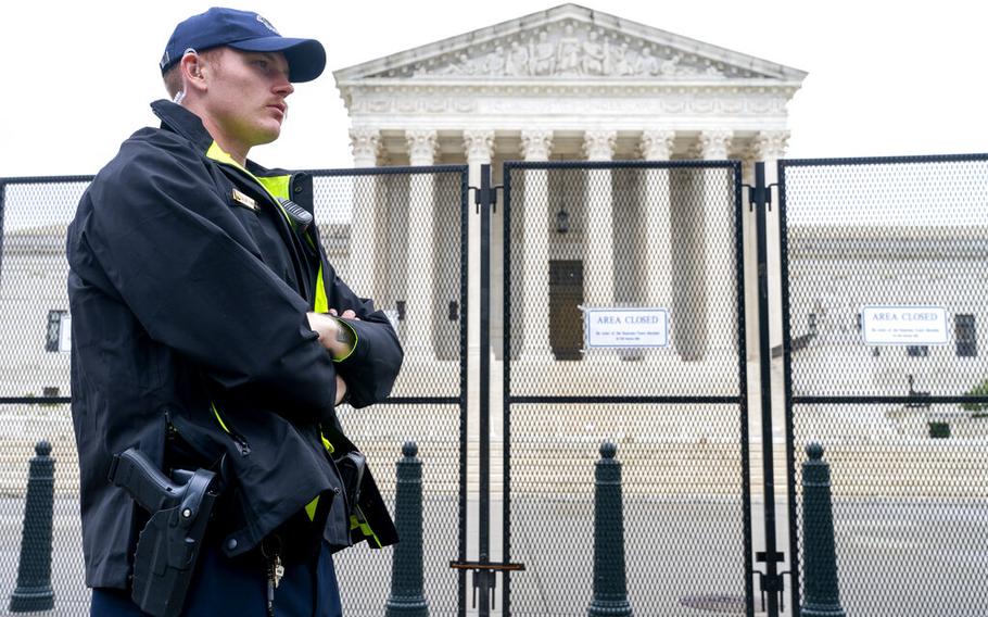 A Capitol Police Officer works by the anti-scaling fencing outside the Supreme Court, Thursday, June 23, 2022, in Washington.