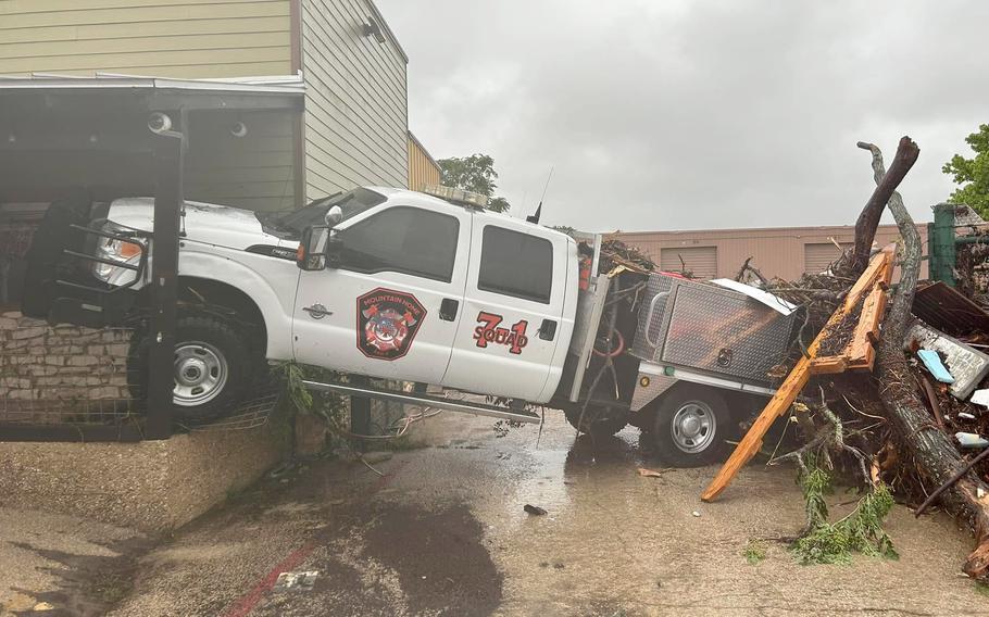 A truck and storm debris piled up against a building.