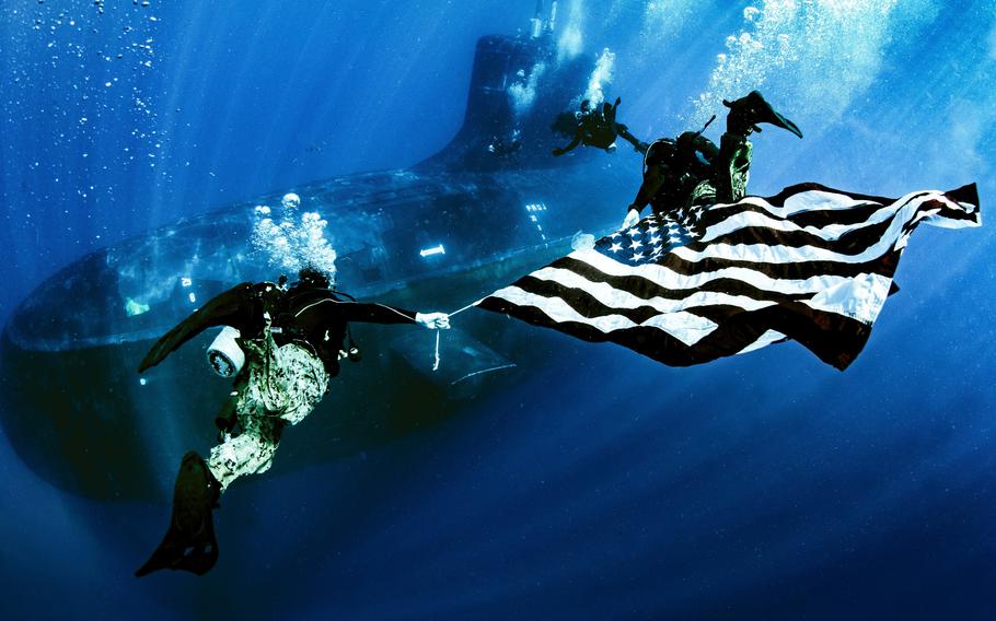 Military members from Naval Special Warfare Group 8 display the national ensign as they perform dive operations while underway on a Virginia Class fast-attack submarine USS New Mexico (SSN 778) in June 2022. The commodore of Naval Special Warfare Group 8 was relieved of his command Wednesday, the service announced.