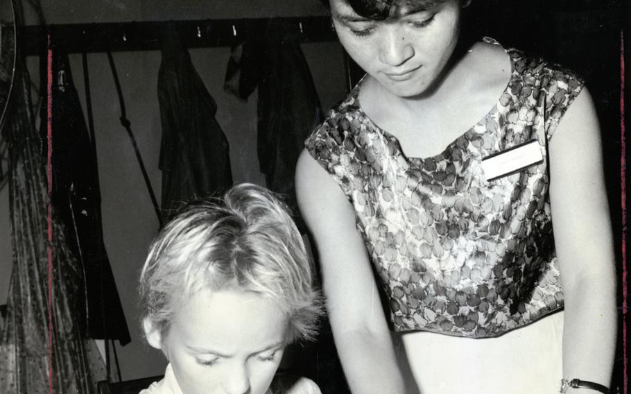 Cheryl Haught, left, a fifth-grade student at Machinato Elementary School on Okinawa, uses a crayon during an origami and drawing class as Okinawan teacher Yoneko Yamazato looks on Sept. 15, 1961. 