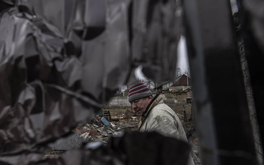 Anatoly Klimashenko tries to repair a metal wall near his damaged home in Lyman on Dec. 18.