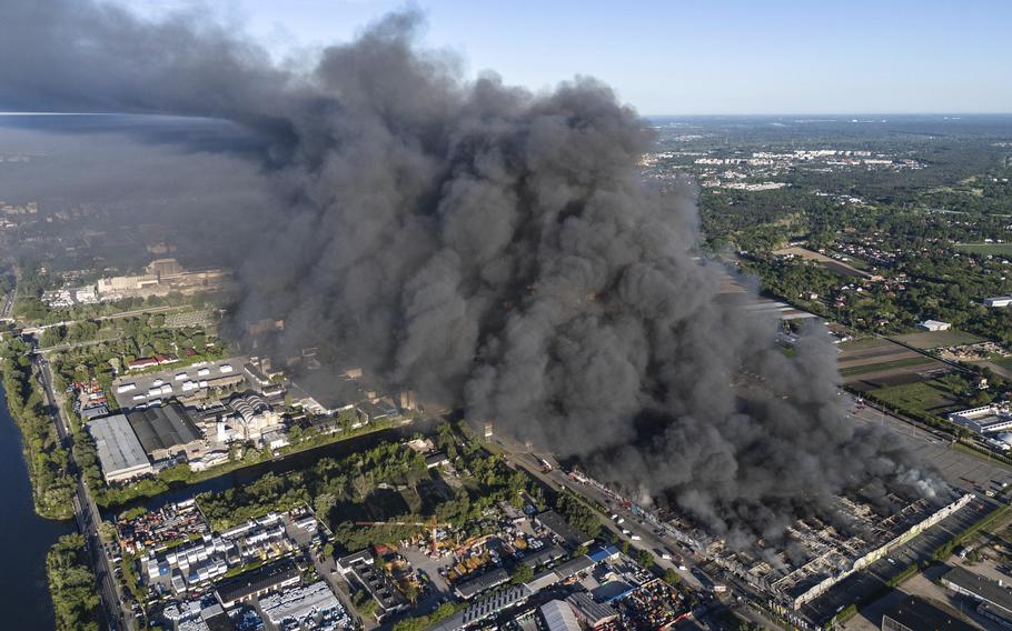 Black smoke rises into the sky above the shopping center.