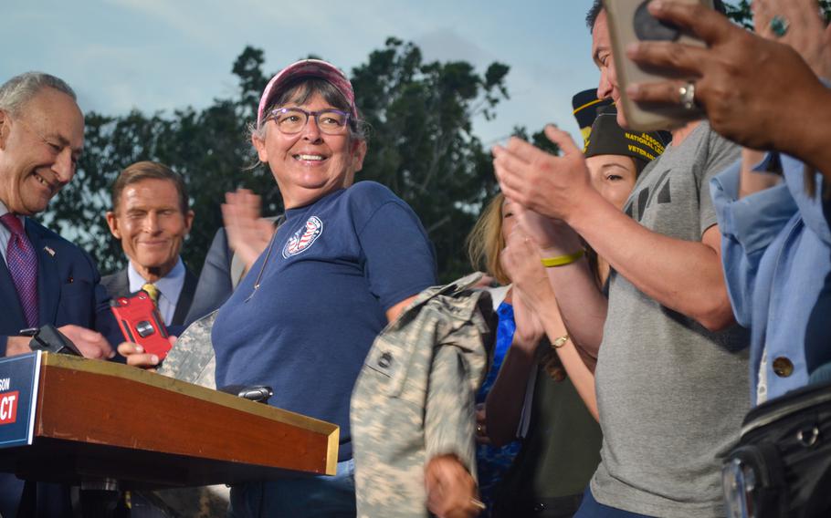 At a news conference Tuesday, Aug. 2, 2022, following the Senate approval of the PACT Act, Susan Zeier takes off an old Army jacket that she wore in support of the legislation. The jacket belonged to her son-in-law, Sgt. 1st Class Heath Robinson, who was diagnosed with a rare autoimmune disorder and lung cancer after serving with the Army National Guard in Kosovo and Iraq, where he experienced prolonged exposure to burn pits. He died in 2020.