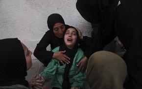 A woman mourns as other women hold and surround her.