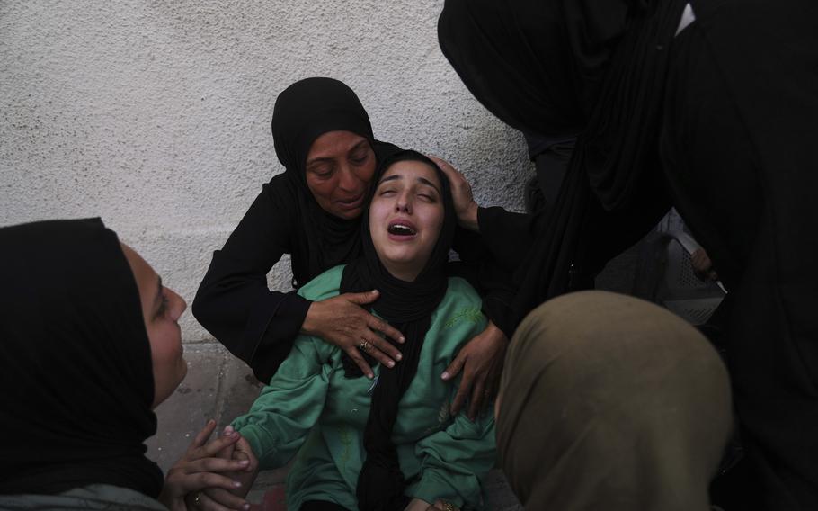 A woman mourns as other women hold and surround her.