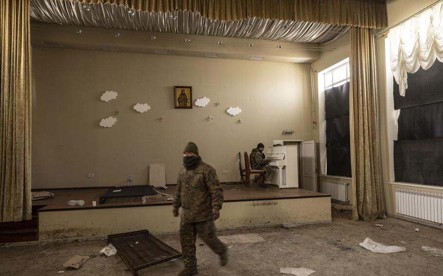 Jon Freedy, a member of the Carpathian Sich 49th Infantry Battalion from Colombia, plays Happy Birthday on the first anniversary of the Russian invasion of Ukraine Friday in a bombed-out church in the country's Donetsk region. His weapon leans against the wall next to him.