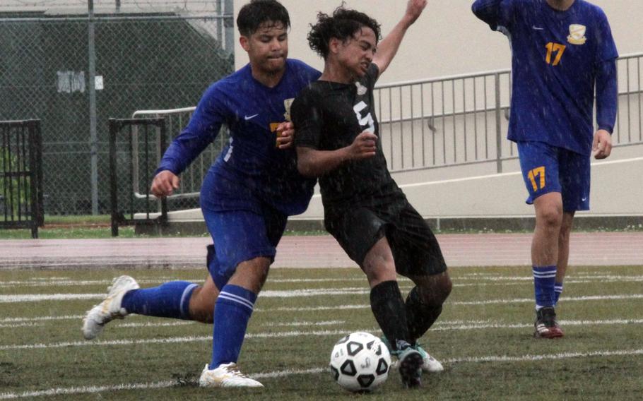 Yokota’s Toby Canales and Daegu’s Kahlel Magsakay battle for the ball in the rain during Monday’s boys Division II soccer match. The Panthers won 1-0.