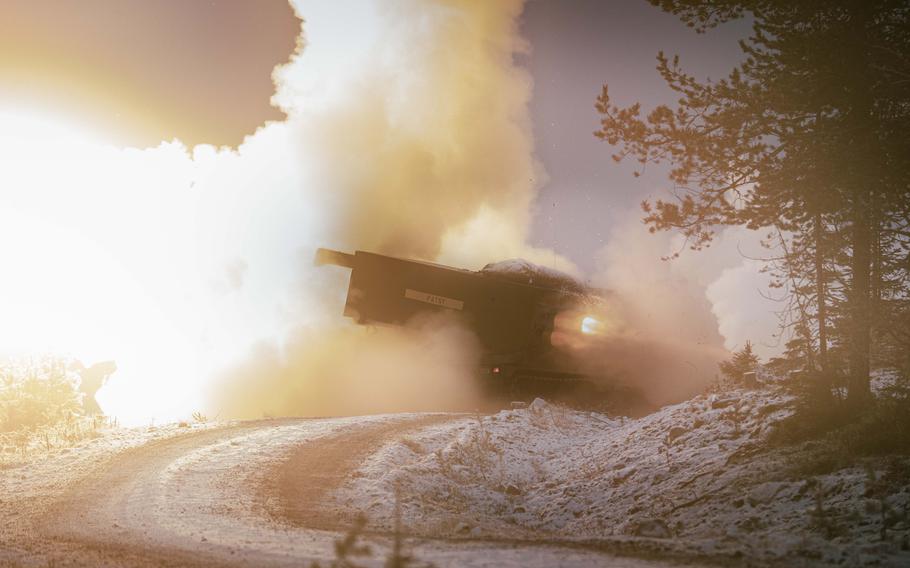 An M270A2 Multiple Launch Rocket System is surrounded by smoke as it fires its first round during training.