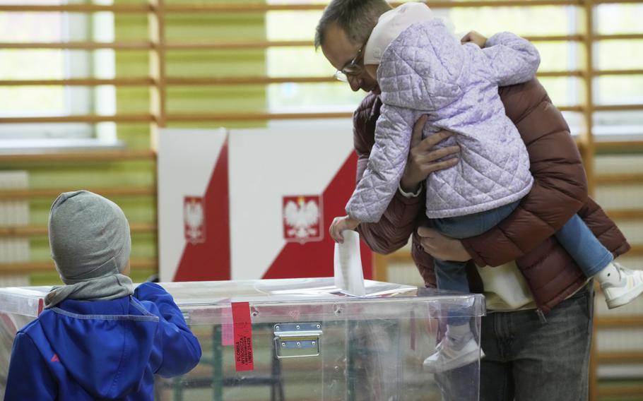 A man with two young children casts a ballot in Poland.