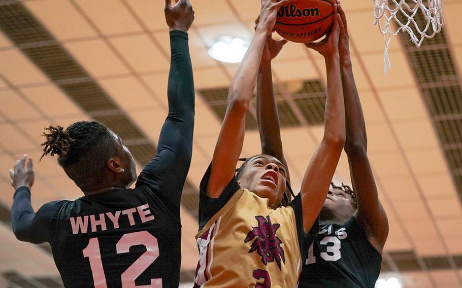 Matthew C. Perry's Billy Hill skies for a shot between Nile C. Kinnick's Nicholas Whyte and Jaelin White during Friday's DODEA-Japan boys basketball game. The Red Devils won 87-53.