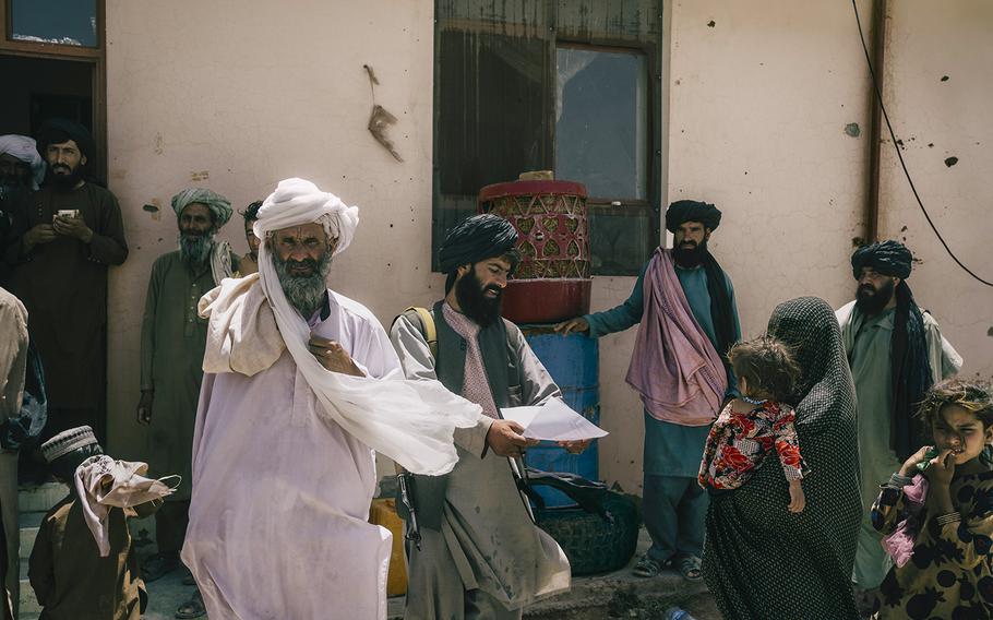 A woman waits with her two young children outside a Taliban court in Marja on June 13, 2022, hoping to secure compensation after her husband was killed in an airstrike. 